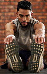 Image showing Gym, portrait of man stretching legs and warm up, workout motivation and fitness mindset with hands on feet. Training, commitment and male athlete on floor, stretch at sports club for exercise goals.