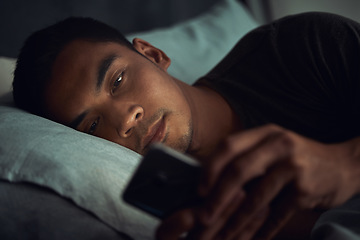 Image showing Night, bed and tired man with phone, internet scroll and social media post or texting, insomnia in home. Wake up, browse and exhausted male in dark bedroom with cellphone, mobile game or digital app.