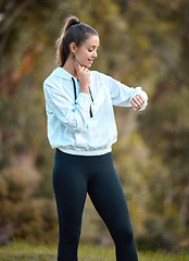 Image showing Fitness, watch and heart rate with a woman runner outdoor checking pulse during a cardio or endurance workout. Exercise, health and bpm with a young female athlete looking at the time while running