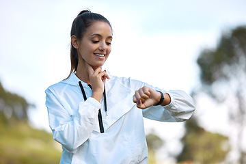 Image showing Fitness, watch and heartbeat with a woman runner outdoor checking pulse during a cardio or endurance workout. Exercise, health and heart rate with a young athlete looking at the time while running