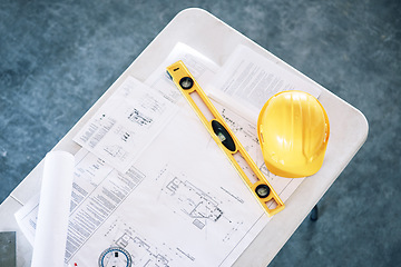 Image showing Blueprint, building and project for construction above, planning or engineering equipment on table at office. Top view of floor plan, hard hat and level for architecture, safety or strategy documents