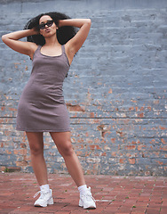 Image showing Fashion, young woman and posing near a wall outside or lady with attitude feeling freedom or happy with sunglasses in city. Urban fashion, cool eyewear and female model with afro or stylish clothing