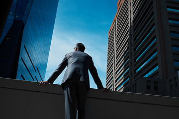 Image showing Business, man and thinking at city on rooftop about career or future with goal in company. Professional, person and skyscraper on roof is standing with vision or hope for decision as leader at work.