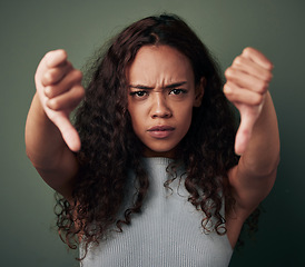 Image showing Woman, thumbs down and angry, fail with hands, disagreement and negative mindset isolated on green background. Female person with bad review, feedback and problem with anger and dislike in studio