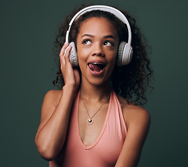 Image showing Music, headphones and gen z girl in studio for streaming, silly face or audio on green background. Podcast and goofy female model relax while listening to radio, audio or online playlist