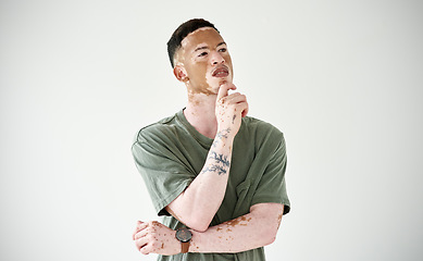 Image showing Memory, man against a studio backdrop and thinking for problem solving. Solution or decision, remember or doubt and isolated young male person with vitiligo against white background for inspiration