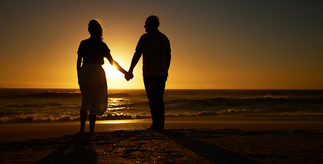 Image showing Beach, sunset and a silhouette couple holding hands on vacation or holiday outdoor. Behind man and woman in nature with creative art, mockup space and ocean for love, care and travel or freedom