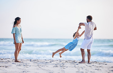 Image showing Mother, beach or father playing with child in air on family holiday, vacation or weekend break together. Parents, mom or dad swinging or bonding with child, daughter or kid at seaside with happiness