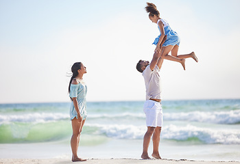 Image showing Mother, beach or father playing a girl in air on a family holiday, vacation or weekend break together. Parents, mom or dad swinging or bonding with child, daughter or kid at seaside with happiness