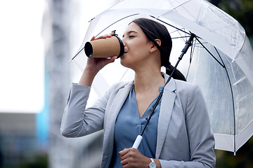 Image showing Business woman is drinking coffee, umbrella and travel with commute to work and person in the city. Young female professional in the rain, enjoying hot drink with traveling, urban and insurance