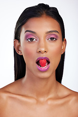 Image showing Woman, makeup and raspberry in mouth for studio portrait, glow color and skincare by white background. Face of indian model eating fruits with bold cosmetics, facial aesthetic and shine for beauty