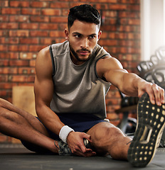 Image showing Fitness, man and stretching legs for warm up at gym with motivation, training and focus mindset. Workout, commitment and athlete on floor with hand on foot leg for exercise goals at sports club