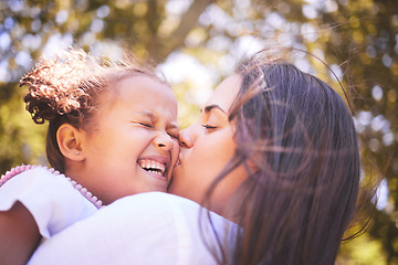 Image showing Mother, child and kiss cheek in nature, funny and bonding in summer garden on holiday. Mom kissing happy girl for love, affection and care of enjoying freedom of quality time together outdoor in park