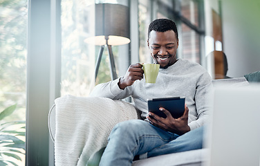 Image showing Relax, coffee and tablet with an african man on a sofa, sitting in the living room of his home to browse social media. Smile, technology or internet with a happy male person relaxing alone in a house