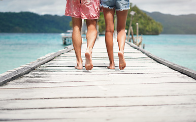 Image showing Couple, feet and ocean pier on a island on vacation with walking freedom by sea. Travel, tropical beach and deck walk of a man back and woman together with love in summer on a holiday outdoor in sun