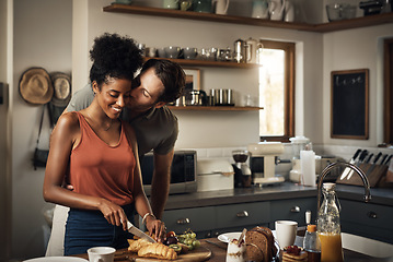 Image showing Interracial couple, kiss and cooking in kitchen for morning breakfast, love or caring relationship at home. Man kissing woman while making food, romantic meal or cutting ingredients on table in house