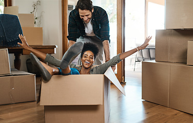 Image showing Happy couple, box and fun for moving to new home, real estate property and celebrate together. Excited man, woman and interracial partner playing in boxes at house for freedom, renovation or mortgage