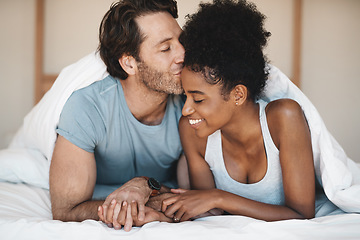 Image showing Happy interracial couple, bed and morning kiss in relax or bonding relationship at home. Man kissing woman on forehead in happiness or embrace for love or relaxing weekend together in the bedroom