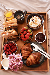 Image showing Breakfast in bed, top view and morning food of croissant, strawberry and drinks for wellness, eating and home cuisine. Hospitality, hotel meal service and tray of bread, coffee and juice in bedroom