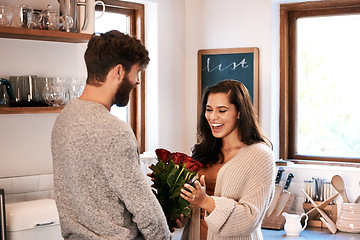 Image showing Roses, kitchen and happy couple with surprise flowers, floral present and flower bouquet for Valentines Day celebration at home. Birthday, smile and romantic man with gift for marriage anniversary