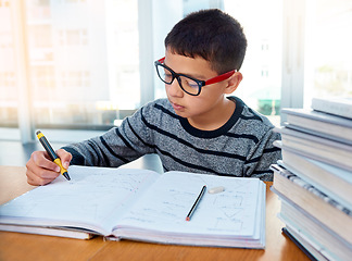 Image showing Boy child, student and writing for studying, homework or learning in education with book on table at home. Smart little kid busy on mathematics, textbooks or problem solving for study in living room