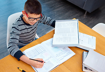 Image showing Happy boy, student and writing on math book for studying, learning or education on table at home. Smart little kid or child busy with mathematics homework, textbook or problem solving on study desk