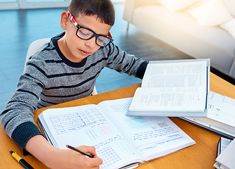 Image showing Child boy, student and writing on math book in studying, learning or education on table at home. Smart little kid busy with mathematics homework, textbook or problem solving on living room study desk