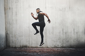 Image showing Jump, training and black man running, speed and energy for cardio fitness, workout and sports wellness or body health. Athlete, runner or person exercise on concrete wall, action run or moving in air