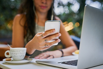 Image showing Closeup, laptop and remote work or hand on phone or a message at a cafe and social media. Female person, freelance and communication or searching on device or email on mobile app and at coffee shop.