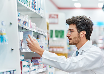 Image showing Pharmacist, reading medicine and man in pharmacy while working in store for retail career. Male person in pharmaceutical or medical industry for service, healthcare and inventory check on shelf