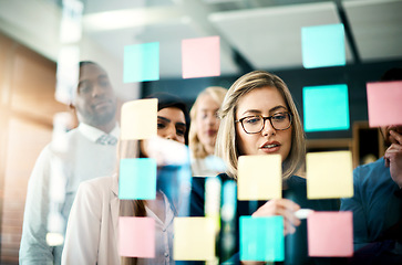 Image showing Manager, sticky note and brainstorming with team on glass for schedule, calendar and planning goals, agenda and timeline. Woman, mentor and collaboration of ideas at window for feedback in office