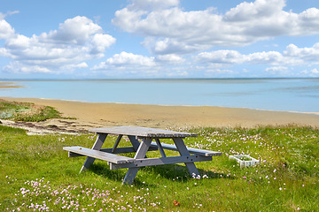 Image showing Picnic table, beach and landscape with nature and travel, environment and coastal location in Denmark. Ocean view, fresh air and natural scenery with seaside destination, land and journey with meadow