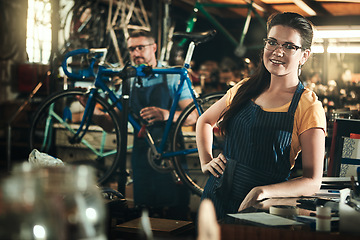 Image showing Portrait, working and smile of woman in bicycle shop, repair store or cycling workshop. Face, bike mechanic and confident person, professional or technician standing with glasses in small business.