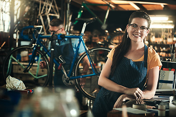 Image showing Portrait, mechanic and smile of woman in bicycle shop, repair store or cycling workshop. Face, bike technician and confident female person, business owner and professional standing with glasses.