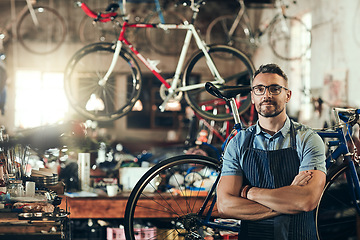 Image showing Portrait, serious and repair man in bicycle shop with arms crossed working in workshop. Face, bike mechanic and confident male person, professional or mature technician with glasses in small business