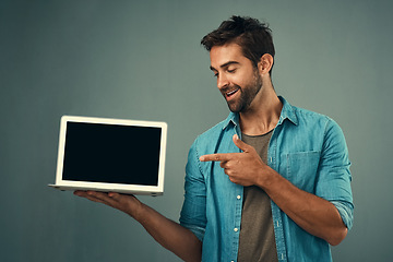 Image showing Happy man, laptop and pointing to mockup screen for advertising or marketing against a grey studio background. Male person smiling and showing technology display or mock up space for advertisement