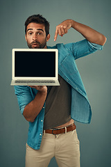 Image showing Man, laptop and pointing on mockup screen for advertising or marketing against a grey studio background. Portrait of a male person showing computer display, mock up and tech space for advertisement