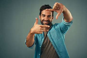 Image showing Frame, hands and face portrait of man in studio on gray background with happiness, confident and smile. Photographer, happy and male person with hand sign for picture, photography and finger border