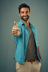 Image showing Happy man, portrait and thumbs up for winning, success or good job against a grey studio background. Male person with smile showing thumb emoji, yes sign or like for approval, thank you or support