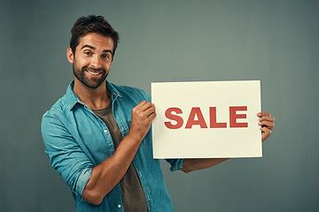 Image showing Happy man, portrait and sale sign for advertising, marketing or branding against a grey studio background. Male person or realtor holding billboard or poster with smile for selling advertisement