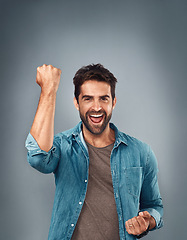 Image showing Happy man, fist and celebration for winning, success or victory against a grey studio background. Excited portrait of male person or winner in achievement, win or accomplishment on mockup space