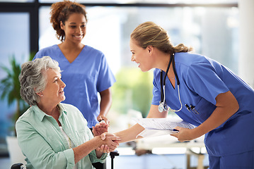 Image showing Handshake, nurse and senior woman in wheelchair with medical results and surgery success news. Hospital, healthcare and clinic with women and nursing staff with care and support of elderly person