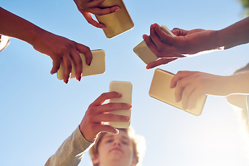 Image showing Hands, below and phone by friends together for social media, networking and sharing app on blue sky background. Low angle, smartphone and gen z people with internet, addiction or online communication