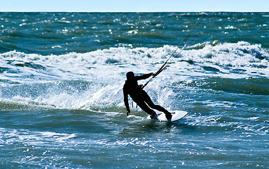 Image showing Silhouette of a kitesurfer on waves of a sea