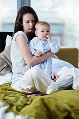Image showing Sad, depression and mother with child in bedroom has fear and stress about infant development in a house. Baby, postpartum and mom in bed is tired from insomnia due to mental health and problem.