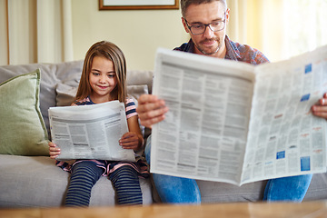 Image showing Father, daughter and reading newspaper on sofa for knowledge, literature or news in living room at home. Happy dad, child and smile for family bonding, learning or education on lounge couch together