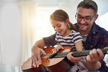 Image showing Father, girl and learning guitar in home, bonding and having fun together. Dad, child and playing acoustic instrument, teaching or education for music lesson, smile and enjoying quality time in house