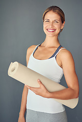 Image showing Happy woman, yoga and portrait smile with mat for exercise, healthy wellness or workout against a grey studio background. Excited female person or yogi smiling for mindfulness, fitness or body health