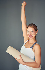 Image showing Happy woman, portrait and yoga mat with fist in celebration for healthy exercise against a grey studio background. Excited female person or yogi with smile for winning, fitness or workout success