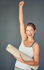 Image showing Happy woman, portrait and yoga with fist in celebration for healthy exercise against a grey studio background. Excited female person or yogi with smile for winning, fitness or workout success at gym